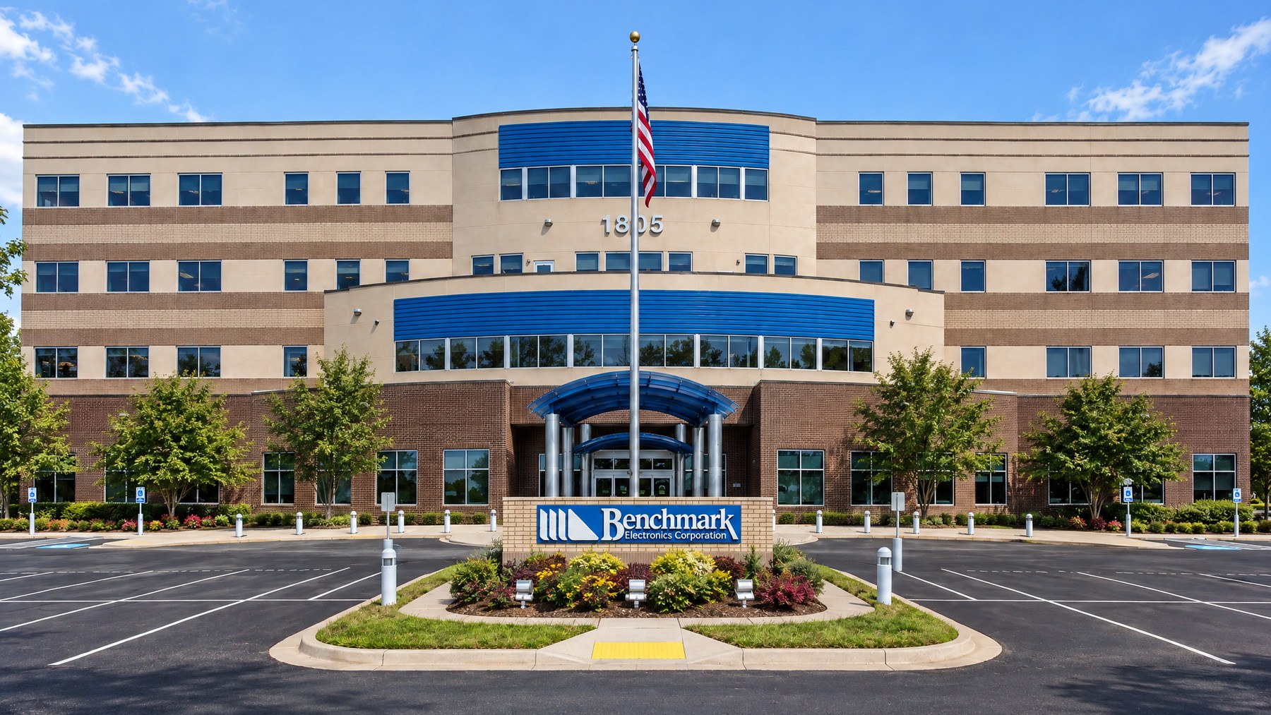 A four-story suburban office building behind its parking lot, brick and glass with a covered entrance canopy